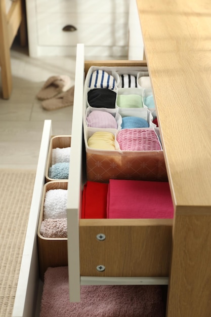 Chest of drawers with different folded clothes indoors closeup
