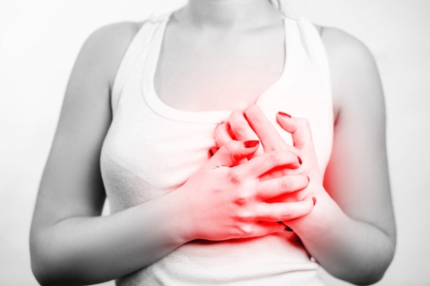 Chest pain, girl in a white T-shirt holds her hands to her chest, red accent on chest,  black and white photography, close-up