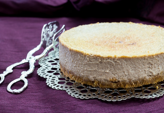 Foto gelato alla cheesecake di castagne su un piatto d'argento e tenaglie di torta sulla porpora