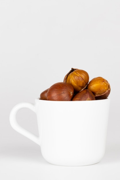 Foto alimento di autunno delle castagne in una tazza su bianco