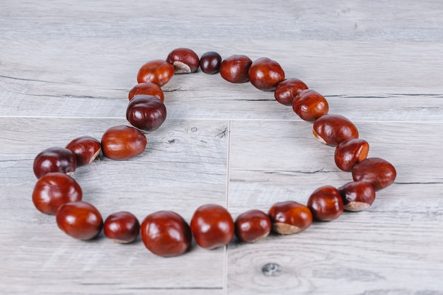 Chestnuts in a heart shape on a wooden background.