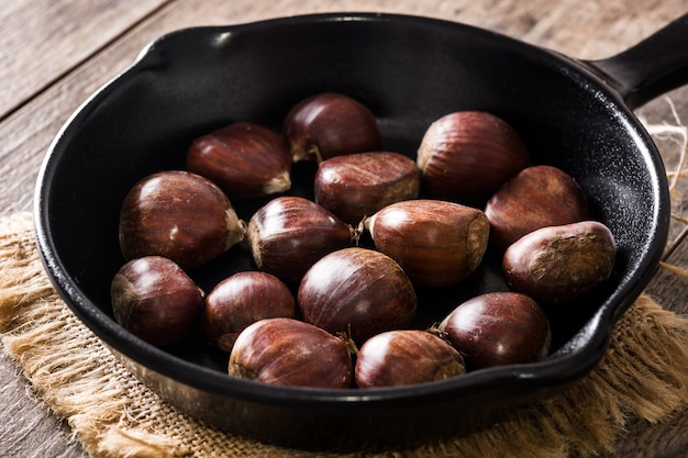 Chestnuts in iron pan on wooden table Close up