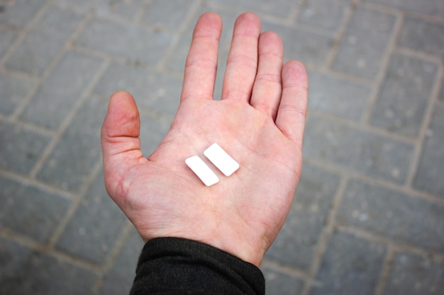 Chewing gum in handTwo white chewing gums on the palm closeup Man's hand holding chewing gum chewing candy