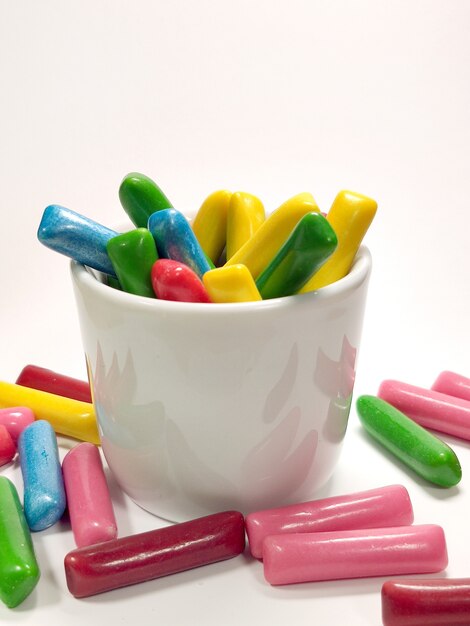 Chewy colored candies in a mug on a white background