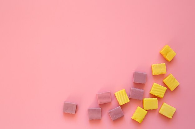 Chewy yellow candies on a pink background.