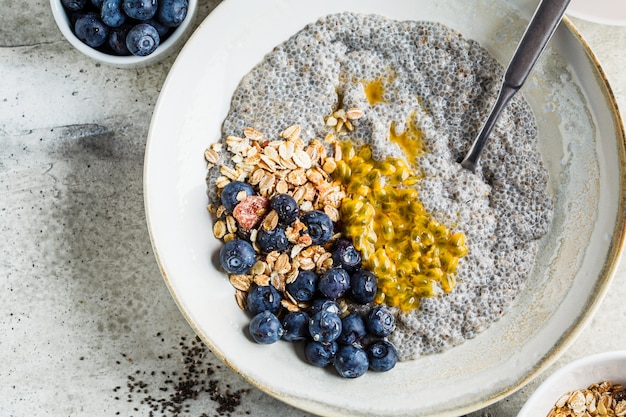 Foto ciotola di budino di chia con mirtilli, frutto della passione e muesli, vista dall'alto. concetto di colazione sana.