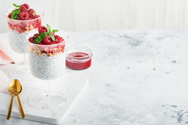 Chia pudding healthy vanilla chia pudding in glass with fresh\
raspberries and mint on white background vegan healthy\
breakfast