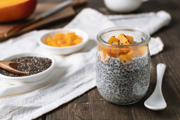 Chia-pudding in glazen pot met amandelmelk en mango op rustieke houten