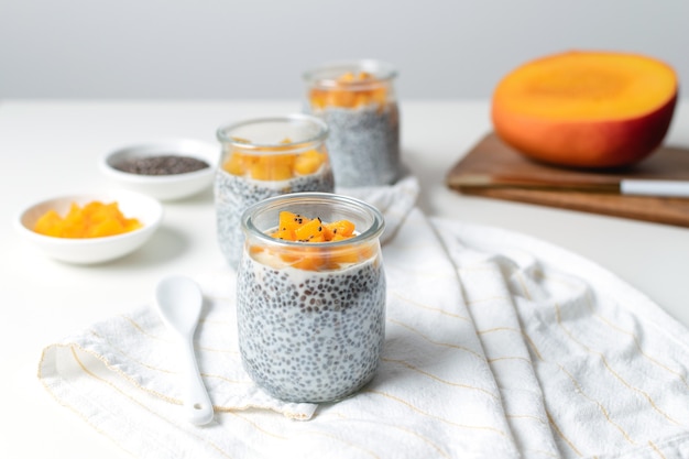 Chia-pudding in glazen pot met amandelmelk en mango op wit