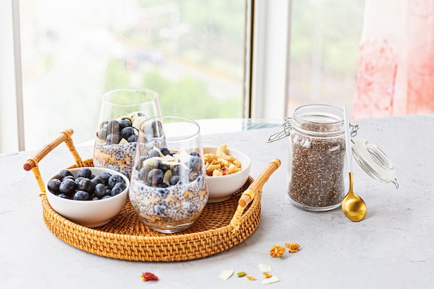 Chia pudding met granola en verse bosbessen in de glazen op een grijze betonnen achtergrond met kopie ruimte. Concept van gezond eten, gezonde levensstijl, dieet, fitness menu. Selectieve aandacht