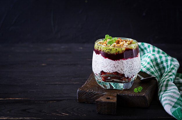 Chia pudding met verse bessen, noten en mint in glas. Gezond ontbijt.