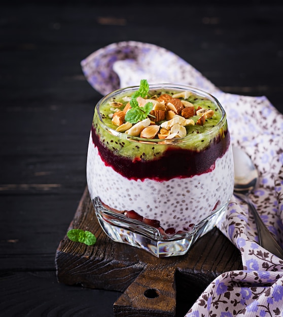 Chia pudding met verse bessen, noten en mint in glas. Gezond ontbijt.