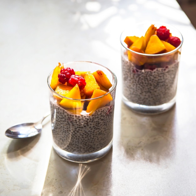 Chia pudding op kokosmelk met frambozen en perzik in glazen potten