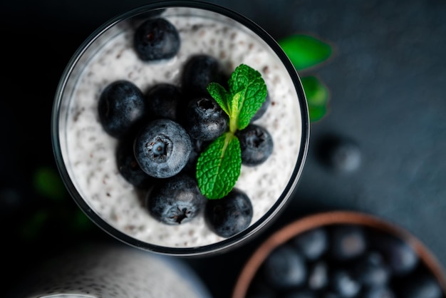 Chia pudding with blueberries on a dark background. Chia pudding, mint and blueberries on a black background. High quality photo