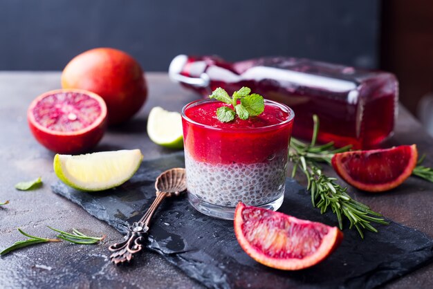 Chia pudding with fresh berries puree and honey with slice citrus on slate dark background