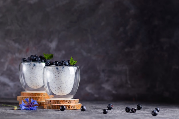 Chia pudding with mint and blueberries in glasses on a wooden stand