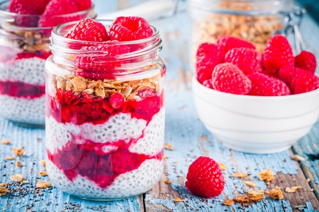 Chia pudding with raspberry sauce granola and fresh raspberries on rusic background