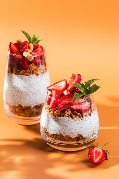 Chia pudding with strawberries and chia seeds on a orange background