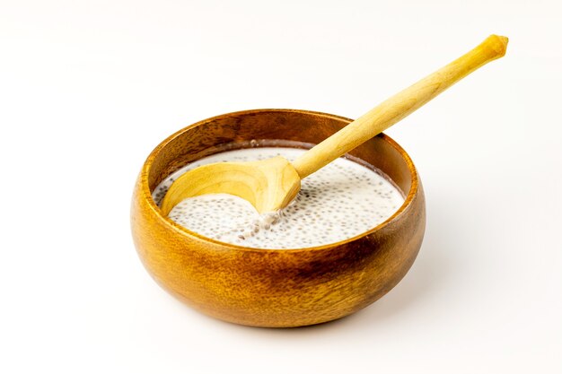 Chia seed milk pudding in bamboo bowl with wooden rustic spoon. Close up. Selective soft focus.  Text copy space.