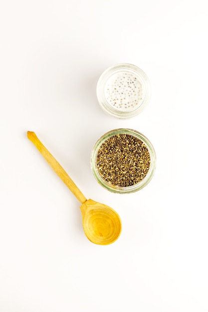 Chia seed milk pudding and dry seeds in small glass bowls with wooden rustic spoon. Top view. Flat lay. Close up. Selective soft focus.  Text copy space.