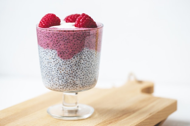 Chia seed parfait pudding with almond milk, yogurt, pink pitaya dragon fruit powder and raspberries dessert in a glass