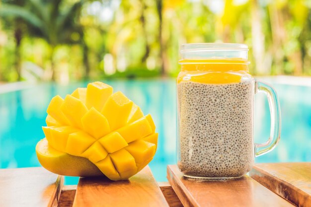 Chia seed pudding with almond milk and fresh mango topping on the background of the pool