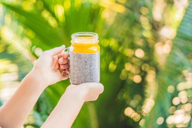 Chia seed pudding with almond milk and fresh mango topping in hand