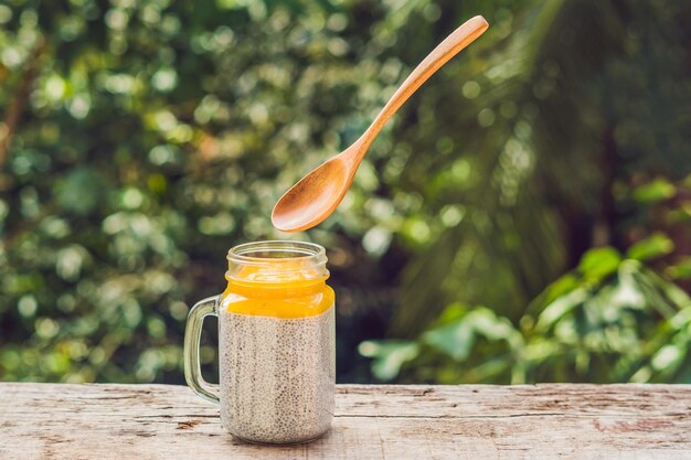 Chia seed pudding with almond milk and fresh mango topping with levitating spoon.