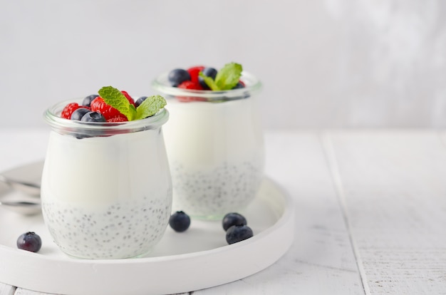 Chia seed pudding with fresh berries on a white wooden table.