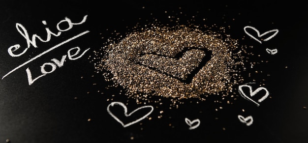 Chia seeds on a black background with the inscription in white chalk on a slate board