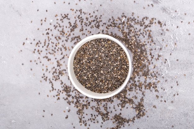 Chia seeds in bowl, on a grey background, top view.