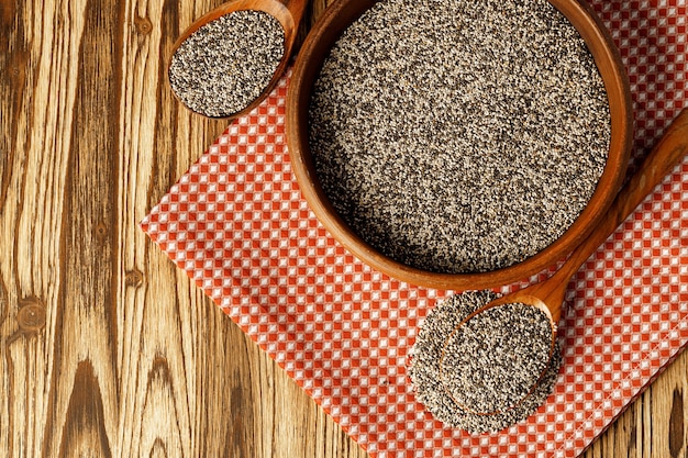 Chia seeds in a bowl with wooden spoon on wooden table