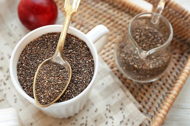 Chia seeds in cup and spoon on wicker tray