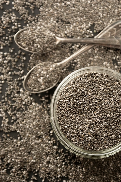 Chia seeds in glass bowl isolated on wooden background, selective focus. Dark background.