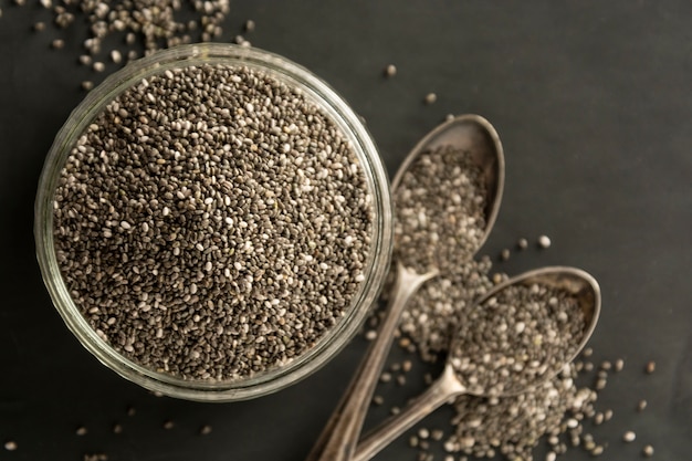 Photo chia seeds in glass bowl isolated on wooden background, selective focus. dark background.