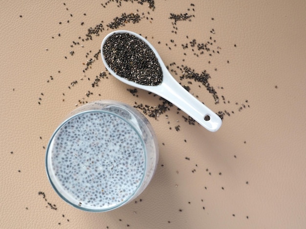 Chia seeds pudding on a beige table and ceramic spoon with dry chia seeds