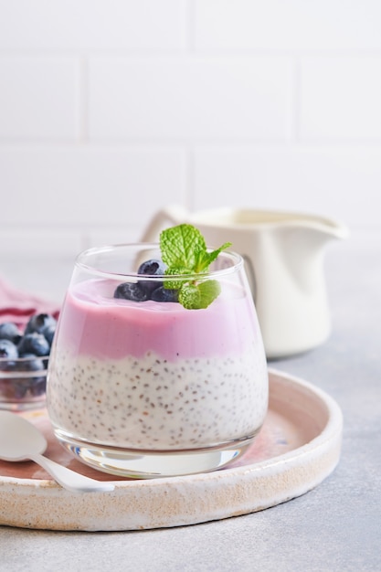 Chia seeds pudding with blueberry yogurt and fresh berries in glass prepared for healthy breakfast. Selective focus.