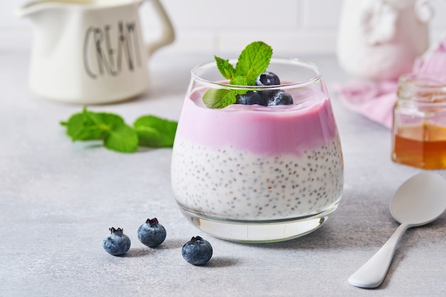 Пудинг из семян чиа с черничным йогуртом и свежими ягодами в стакане, приготовленный для здорового завтрака. Выборочный фокус.