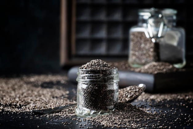 Chia seeds in small glass jar gray background selective focus