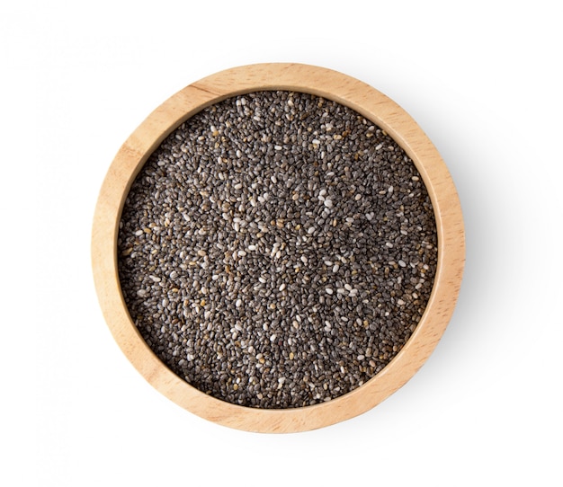 Chia seeds in wooden bowl on white wall. 