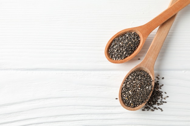 Chia seeds and wooden spoons on white wooden