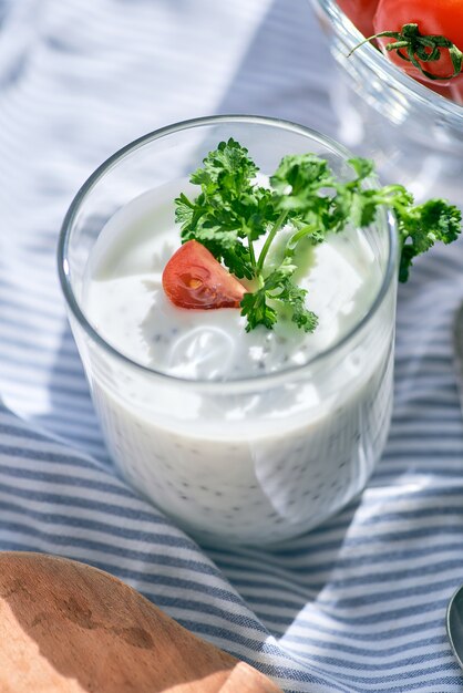 Chia seeds and yogurt in a glass with greens and tomatoes