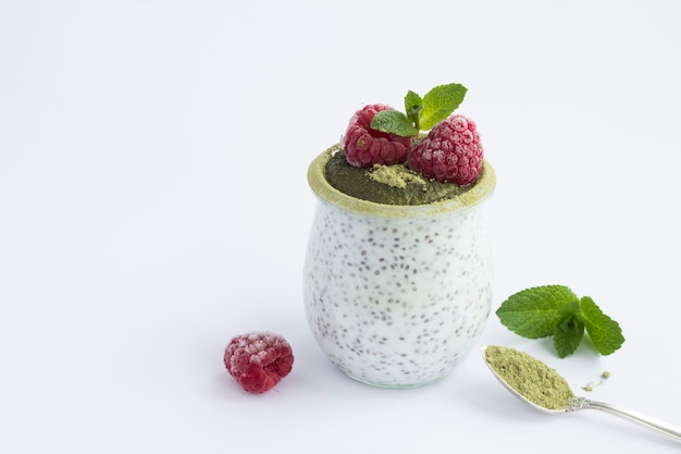 Chia-zaadpudding met framboos en matcha-thee in de glazen pot op wit wordt geïsoleerd. Detailopname. Kopieer ruimte.