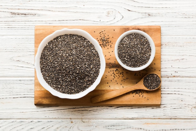 Chia zaden in kom en lepel op gekleurde achtergrond Gezonde Salvia hispanica in kleine kom Gezonde superfood