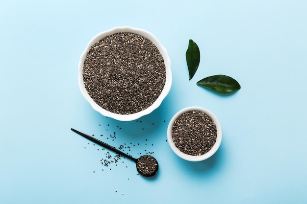 Chia zaden in kom en lepel op gekleurde achtergrond Gezonde Salvia hispanica in kleine kom Gezonde superfood