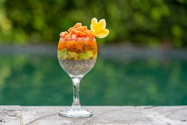 Chia zaden pudding met papaya passievruchten mango en avocado in een glas voor het ontbijt op de achtergrond van het zwembad water close-up Het concept van gezond eten superfood