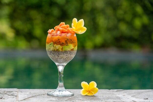 Chia zaden pudding met papaya passievruchten mango en avocado in een glas voor het ontbijt op de achtergrond van het zwembad water close-up het concept van gezond eten superfood