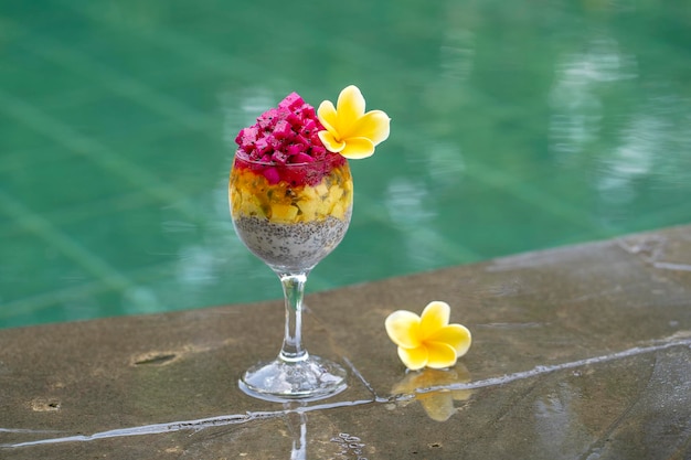 Chia zaden pudding met rode dragon fruit passievrucht mango en avocado in een glas voor het ontbijt op de achtergrond van het zwembad water close-up Het concept van gezond eten