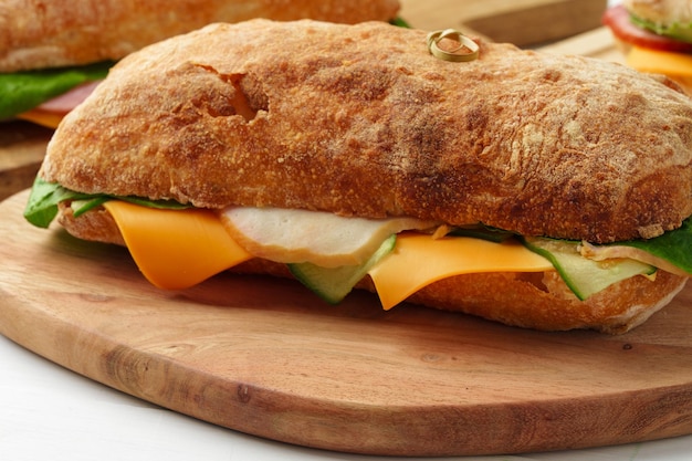 Photo chiabatta sandwich with ham and cheese on wooden board