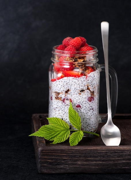 Chiapudding met frambozen en aardbeien in een glazen pot en granola